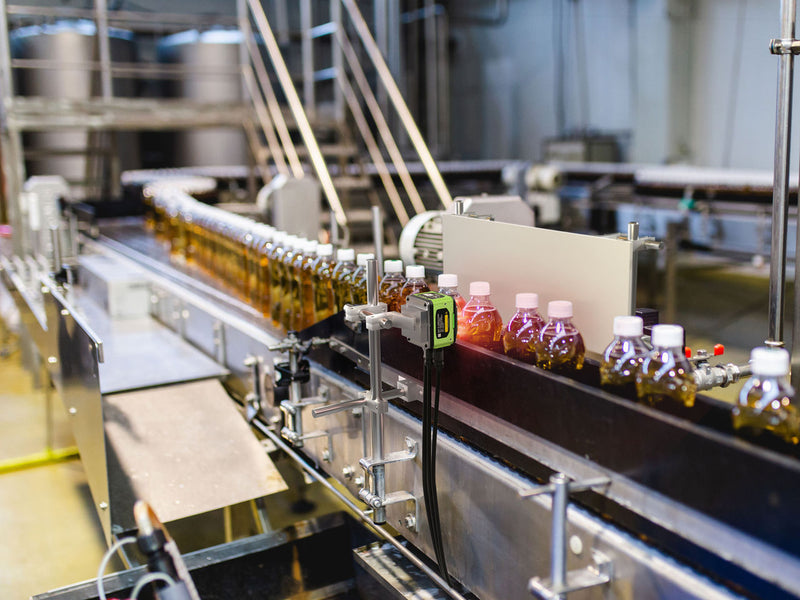 Bottles with liquid inside on conveyer belt being scanned 